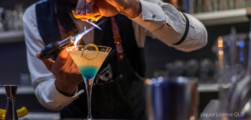 Bartender preparing a cocktail with citrus and a flame