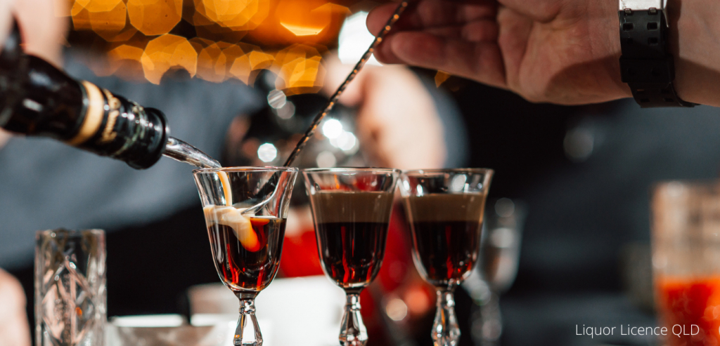 The bartender makes cocktails with liquor, using a bar spoon